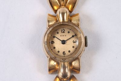 a gold clock with a bow on it on a white surface