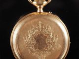 a close up of a gold pocket watch on a black surface