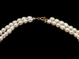a close up of a necklace with pearls on a black background