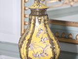 un vase jaune posé sur une table, avec un miroir en arrière-plan