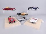 four different model cars on display on a wooden stand