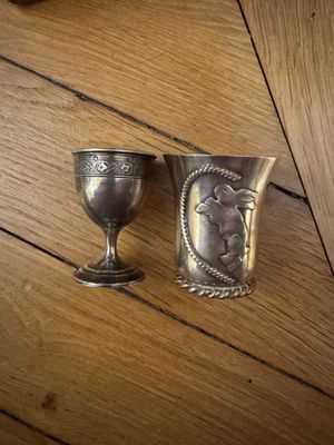 deux gobelets en argent posés sur une table en bois