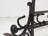 a black iron bench with a scrolly design on it