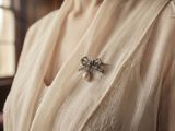 a close up of a woman ' s shirt with a pearl brooch on it