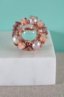 Bague en quartz rose et perle posée sur un bloc de marbre blanc