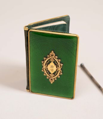 a small green book with a gold medallion on it