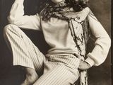 black and white photograph of a woman sitting on a chair wearing a hat
