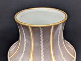 beige and white vase with gold trim on a black background