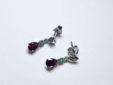 deux paires de boucles d'oreilles ornées de cristaux violets et verts sur un fond blanc