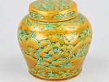 yellow and green vase with flowers and leaves on the lid