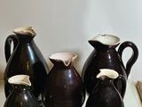 five vases sitting on a glass table with a mirror