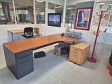 a desk with a computer monitor and a chair in the corner
