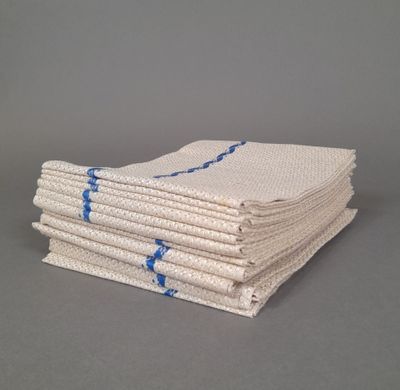 plusieurs serviettes blanches empilées les unes sur les autres sur une surface grise