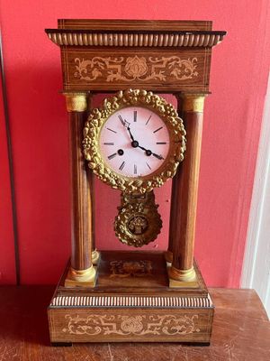 une horloge posée sur une table devant un mur rouge