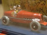a red toy car in a glass case on a table