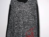 a black and white sweater with a red flower on it