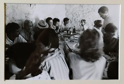 photographie en noir et blanc représentant un groupe de personnes assises autour d'une table
