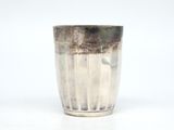 une tasse en argent posée sur une surface blanche