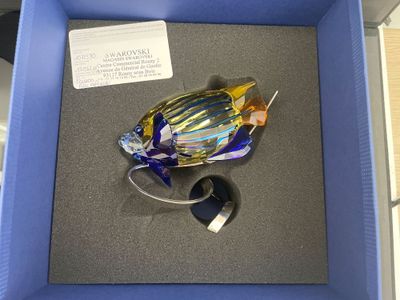 un objet en verre dans une boîte bleue avec une souris