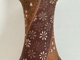 a brown vase with flowers on it sitting on a table