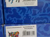 trois boîtes bleues ornées d'une vache, posées sur une étagère