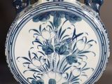 a blue and white vase on a table with a lamp on it