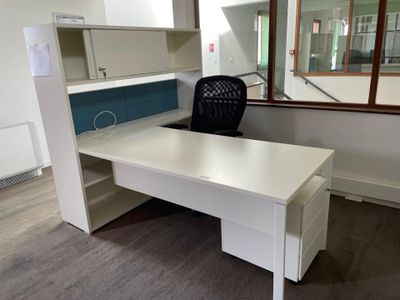 a white desk with a black chair in an office