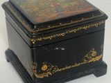 boîte décorée de noir et d'or, posée sur un socle, sur fond blanc