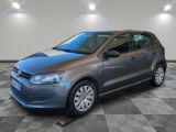 La Volkswagen Polo grise est garée dans une grande pièce au sol carrelé en damier.