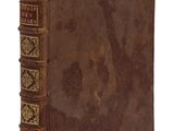 un vieux livre à la couverture brune posé sur une surface blanche