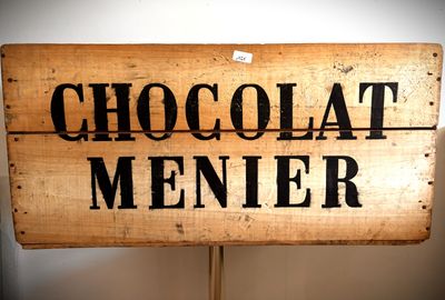 une enseigne en bois sur laquelle est inscrit « Chocolate Menier »