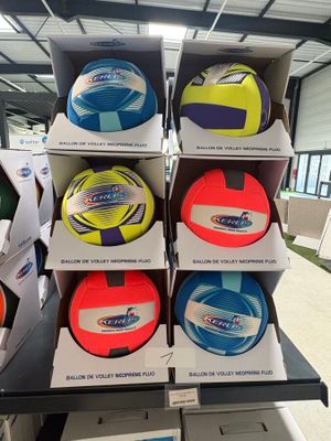 Des cartons de ballons de football sont empilés sur une table dans un magasin.