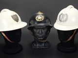 trois casques de pompier blancs posés les uns à côté des autres sur une tête de mannequin