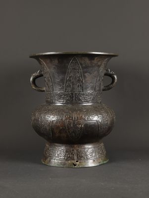 an old metal vase sitting on top of a table next to a gray wall
