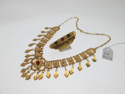 un gros plan d'un collier et d'un bracelet en or posés sur une surface blanche