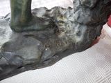 a bronze statue of a person on a rock