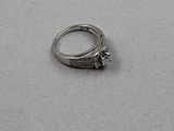 une bague en argent sertie d'un diamant, posée sur une table
