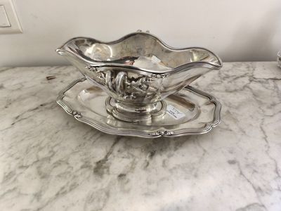 une assiette en argent posée sur une soucoupe, le tout posé sur une table en marbre