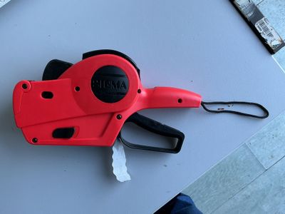 une agrafeuse manuelle rouge et noire posée sur une table