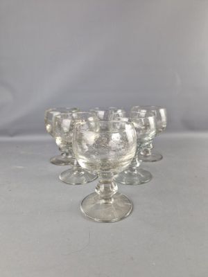 six verres à pied en verre transparent sont alignés sur une surface blanche