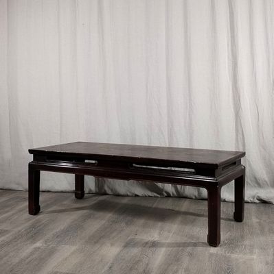 une table basse avec un tiroir, placée devant un rideau blanc