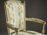 an old chair with a floral upholstered back and arms