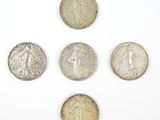six types différents de pièces d'argent sur une surface blanche