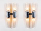 two black and clear glass sconces mounted on a white wall