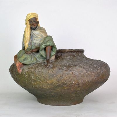a statue of a woman sitting on top of a vase