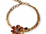 a close up of a gold bracelet with flowers on it