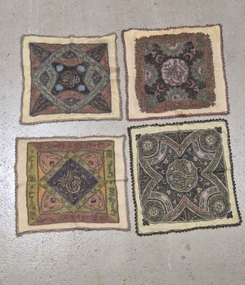 quatre morceaux de tissu carrés, ornés de motifs différents, posés sur le sol
