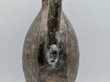 an image of a stone vase with a face on it