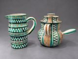 two green and white vases sitting next to each other on a gray surface