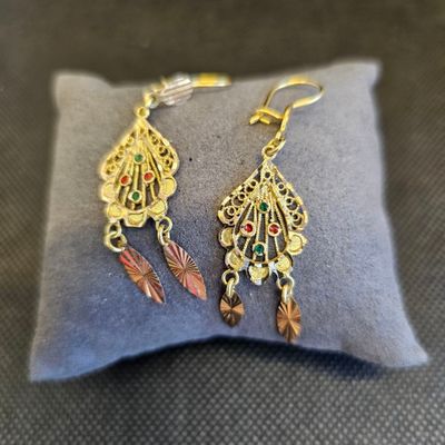 un gros plan sur une paire de boucles d'oreilles posées sur un oreiller